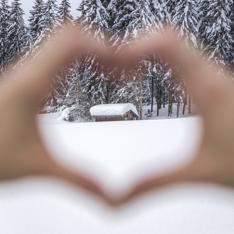 Heart formed with the hands, background hut